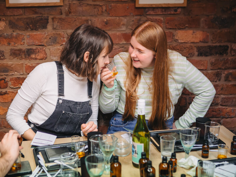 Women smelling essential oils in beakers